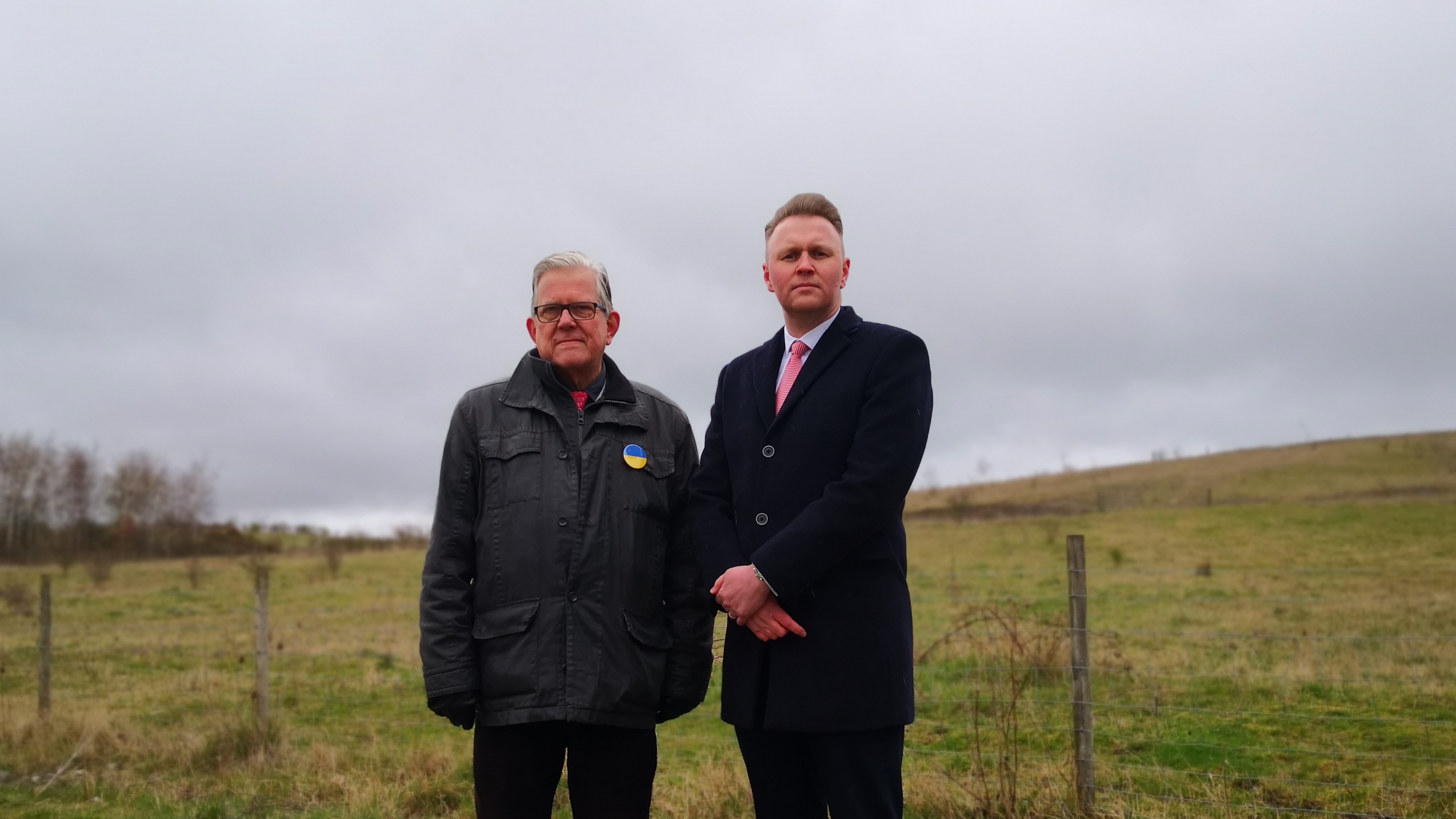 Councillor John Clarke MBE and Councillor Michael Payne stood in front of a field at Gedling Country Park which will become a new Holocaust Memorial Garden